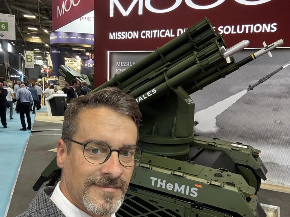David Ertler auf der Eurosatory 2026 vor einem unbemannten Landsystem mit Effektortraeger