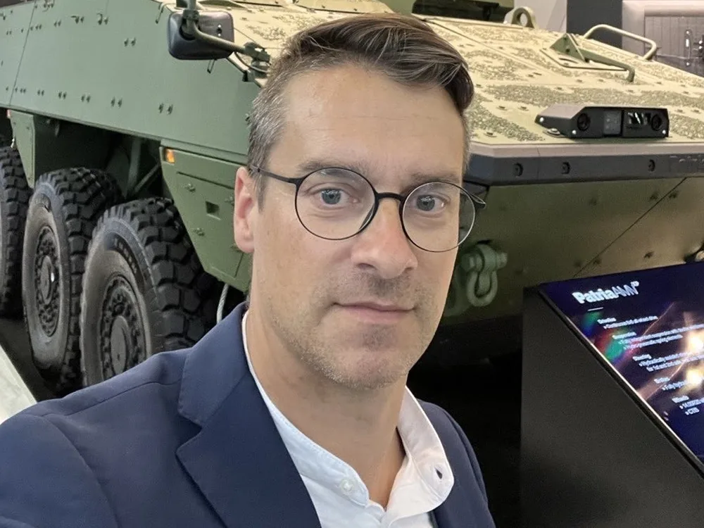 David Ertler auf der Eurosatory 2022 vor einem Radschuetzenpanzer von Patria